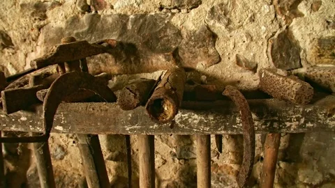 In an old Workshop Rusty tools are in an Rack. The tools are covered by Sand and Stock-Footage 80715853