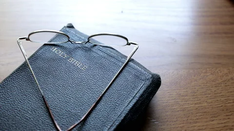 Old worn bible with reading glasses Stock Footage 138462109