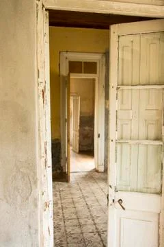 An old worn door open into an empty room with antique ceramic tile floor Stock Photos