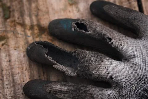 Old worn-out work gloves lying on the board Stock Photos