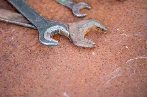 Old wrenches on a rusty sheet of metal, close-up, selective focus. Stock Photos