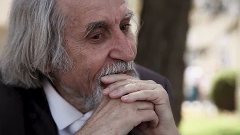 Old wrinkled man with a beard thinks in his arms 库存影片 96468745