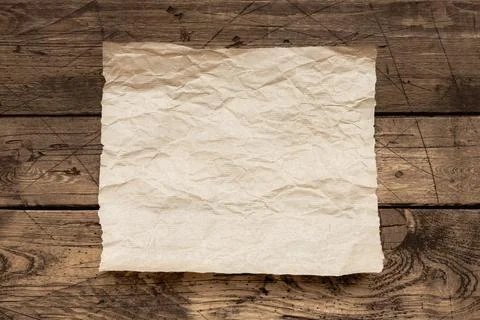 Old wrinkled paper sheet on rustic wooden table, vintage background texture for Foto stock