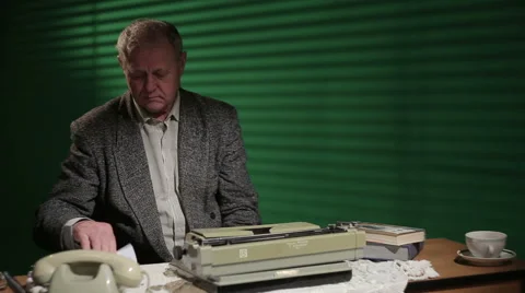 The old writer puts the sheet in a typewriter and begins to write Stock Footage 53268758