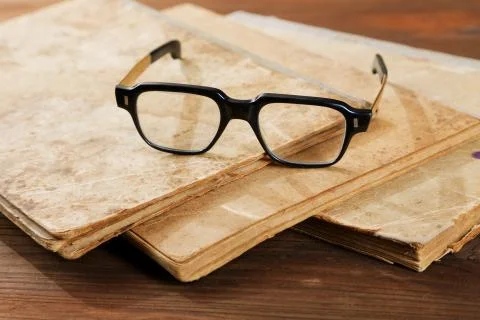 Old writing-books and glasses on a wooden table Stock Photos