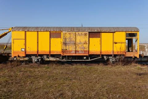 Old yellow cargo train wagon, grungy and weathered on the abandoned train tracks Foto stock
