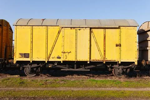 Old yellow cargo train wagon, grungy and weathered on the abandoned train tracks Stock Photos