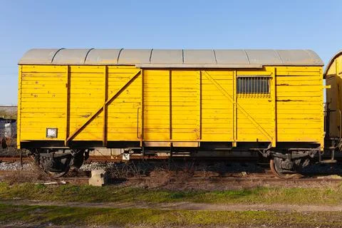Old yellow cargo train wagon, grungy and weathered on the abandoned train tracks Foto stock