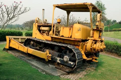 Old yellow rusty crawler tractor in the field. Old crawler tractor on green g Stock Photos