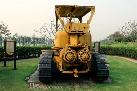 Old yellow rusty crawler tractor in the field. Old crawler tractor on green g Stock Photos