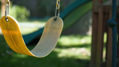 Old yellow swing moving gently swaying in the breeze outdoor in garden summer Video stock 95032720