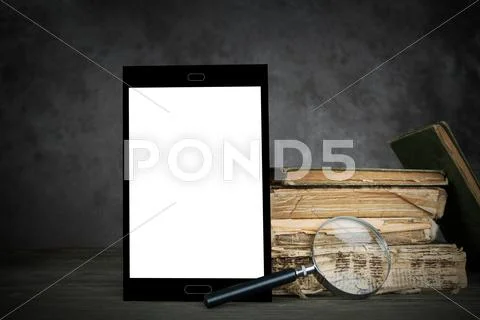 Old Yellowed Books,a Blank Tablet Computer And A Magnifier