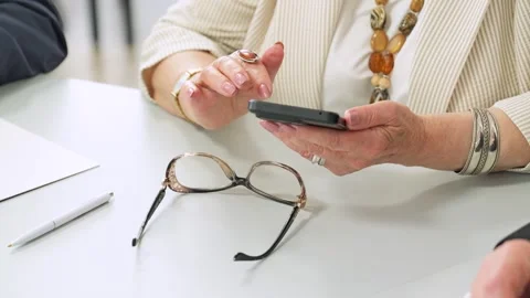 Older adults discovering digital tools. Mature woman in jewelry using smartphone Stock Footage 314750350