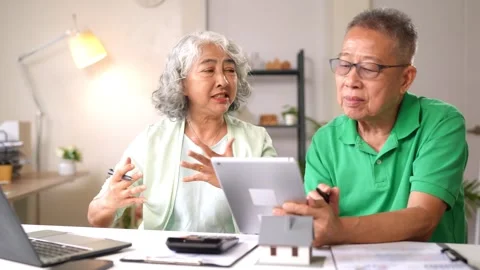 Older Asian couple comparing tablet data with printed documents for home pl.. Stock Footage 333470942