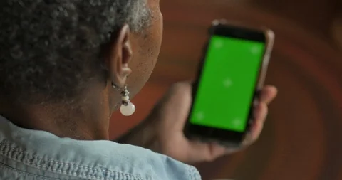 Older black woman looking at her smart phone with a chroma key greenscreen Stock Footage