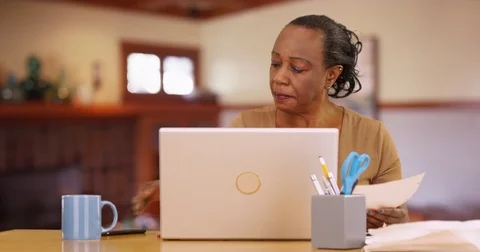 An older black woman working on her laptop in her living room Stock Footage