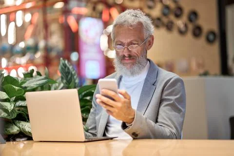 Older business man executive using mobile phone working late in office. Stock Photos