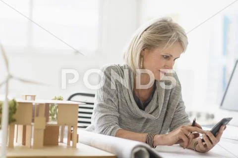 Older Caucasian Architect Using Cell Phone In Office