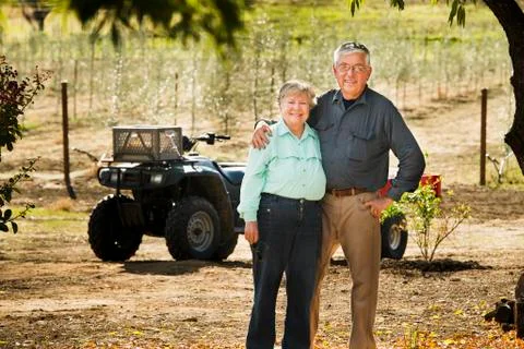 Older Caucasian couple smiling in olive grove Stock Photos