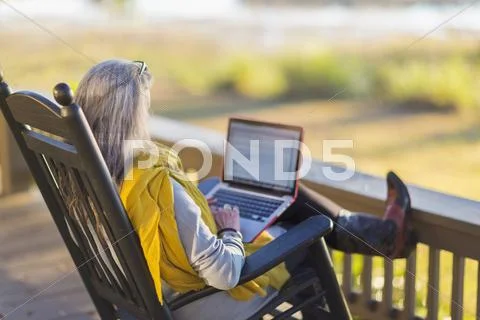 Older Caucasian Woman Using Laptop On Porch