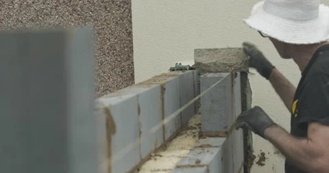 Older construction worker on building site using rope and brick Stock Footage 246380425