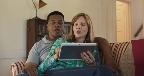 Older couple on the couch using tablet computer together to browse the internet Stock Footage 116900774