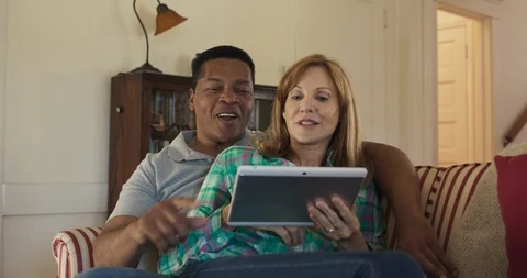 Older couple on the couch using tablet computer together to watch funny video Stock Footage 116901422