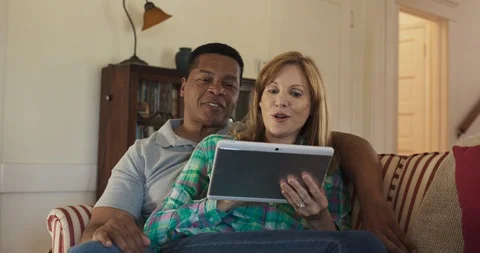 Older couple on the couch using tablet computer together to browse the internet Stock Footage 116901740