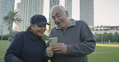 Older couple doing video chat on their cell phone at a park in Florida Stock Footage 234530683