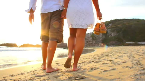A older couple walk the beach barefoot in Mexico during sunset Stock Footage