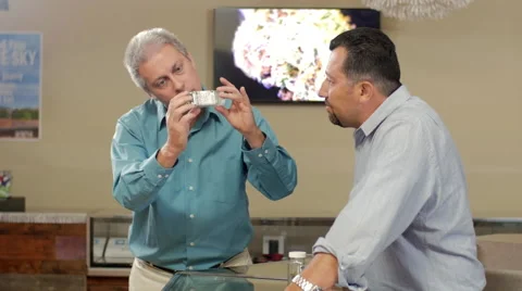Older customer at marijuana shop looking closely at product, smelling it Video stock 59172313