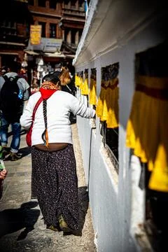 Older devotee turning prayer wheels in Boudhanath Stupa in Kathmandu, Nepal. Stock Photos