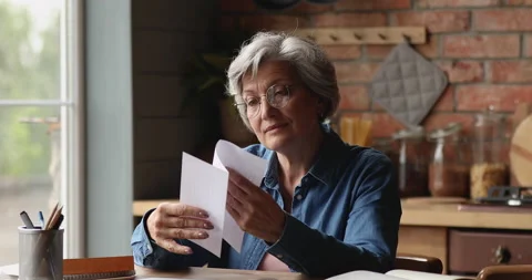 Older female opened envelope reads letter smiles looks pleased Stock Footage 147109040