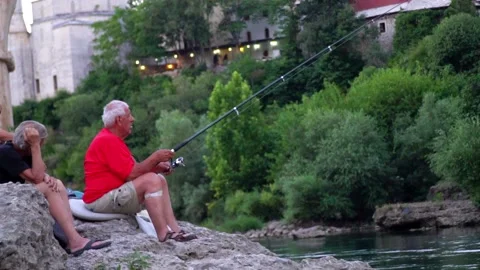 Older guy catching fish under the historical Mostar bridge Stock-Footage 159294507