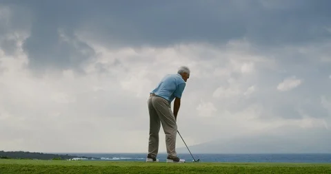 Older Handsome golf takes a swing on beautiful golf course Stock Footage
