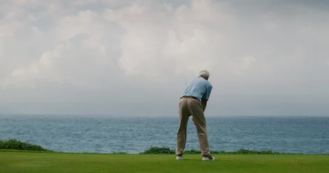 Older Handsome golf takes a swing on beautiful golf course Stock Footage 102409400