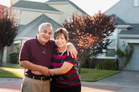 Older Hispanic couple smiling outside suburban home Stock Photos