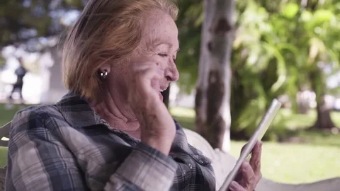 Older Lady smiling and using tablet - Steadicam &amp; slow motion Video stock 74885560
