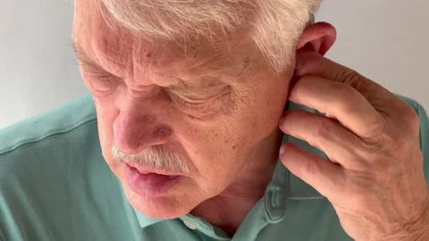 Older man adjusts both hearing aids Stock Footage 219240351