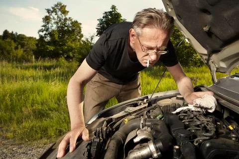 Older man alone on route checking unfunctional engine in late summer light Stock Photos