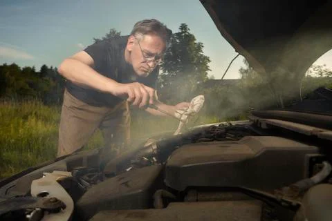 Older man alone on route checking unfunctional engine in late summer light Stock Photos