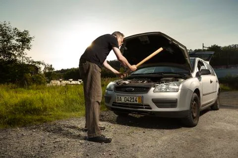 Older man alone on route checking unfunctional engine in late summer light Stock Photos