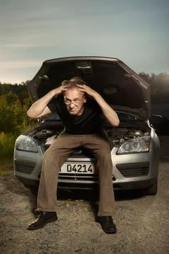 Older man alone on route checking unfunctional engine in late summer light Stock Photos