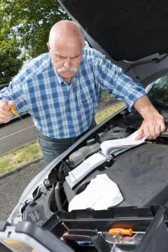 Older man checking levels and servicing his car Foto stock