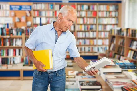 Older man choosing books in bookstore Stock Photos