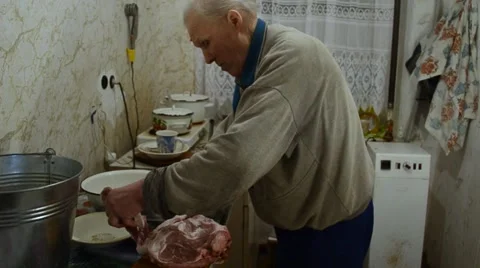 Older Man Cuts a Huge Piece Meat Into Many Small With a Knife Standing in the Stock Footage 61523499