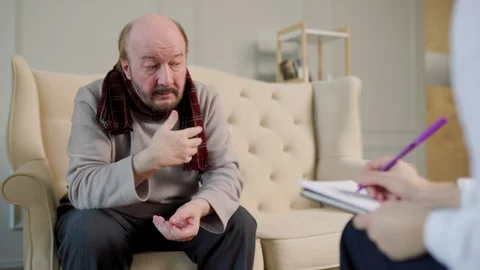 Older man discussing personal issues during therapy session in cozy setting Stock Footage 302969784