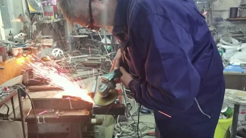 An older man grinds with angle grinder indoor Stock Footage 170580657