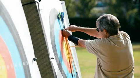 Older man hitting target while practicing archery Stock Photos