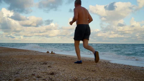 An older man jogging on the sandy beach at the crack of dawn. Stock Footage 313150809